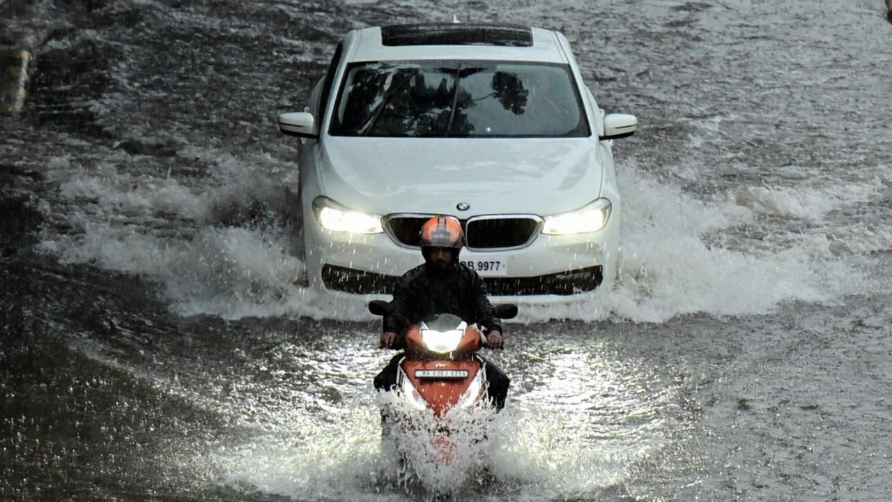 Vehicles move through the waterlogged road following heavy rains in Mumbai on Sunday. Pics/Shadab Khan