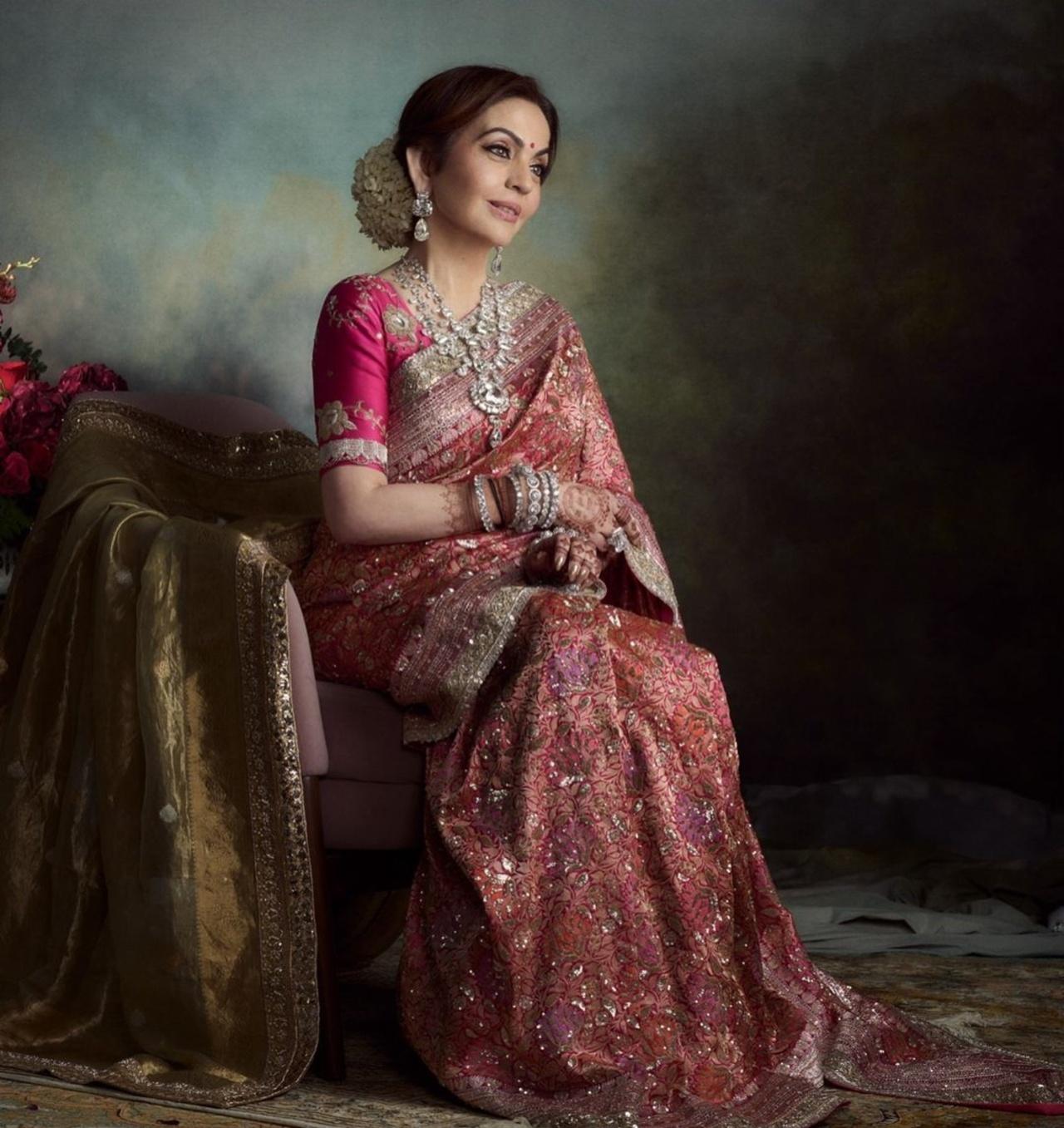 For the wedding reception, Nita wore a custom pink multi-resham kadhwa floral woven brocade saree by Manish Malhotra. The saree was embellished with intricate real silver embroidery. 