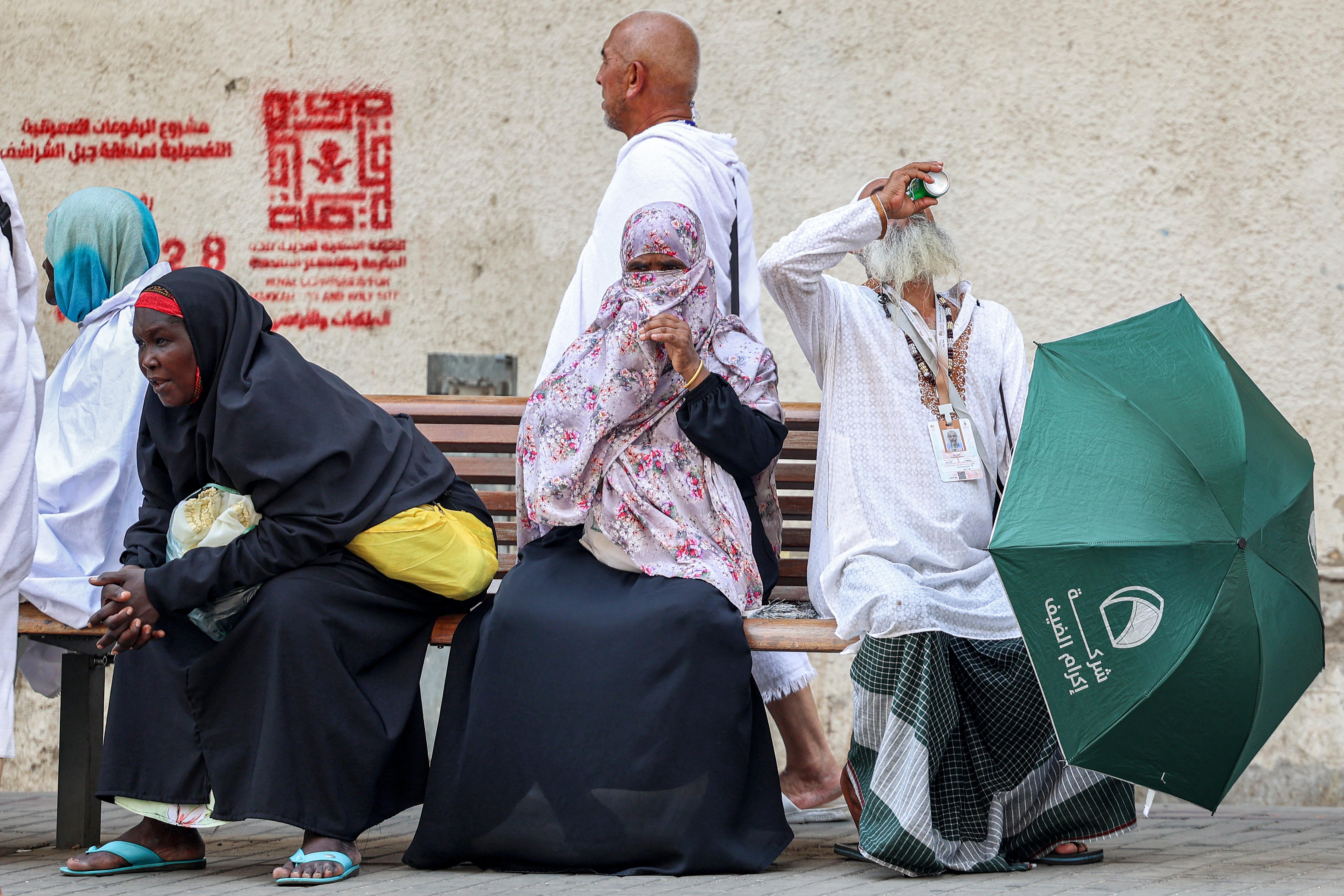 A departing Muslim pilgrim has a drink from a man as he sits next to other women in Saudi Arabia's holy city of Mecca on June 20.