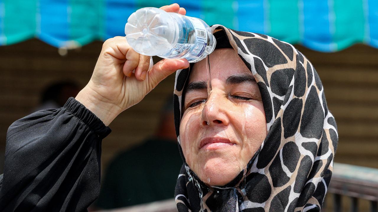 A departing Turkish Muslim pilgrim pours cold water from a bottle on her head to cool off as she waits in Saudi Arabia's holy city of Mecca on June 20.
