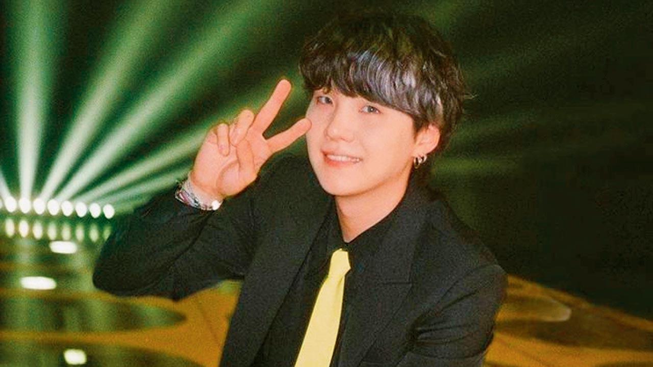 Suga of the boyband BTS adds a pop of yellow to his all-black attire with a tie