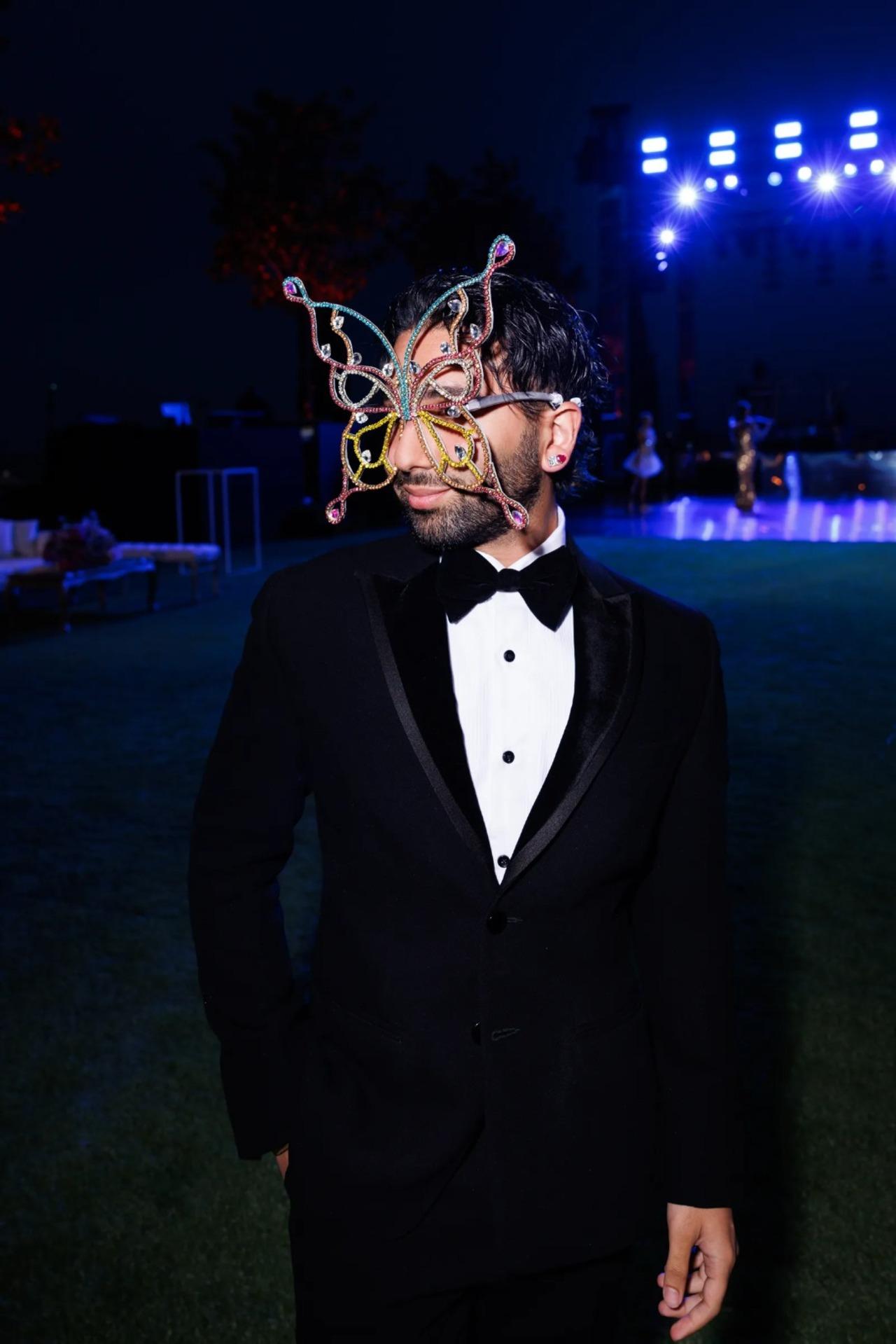 Orhan 'orry' Awatramani poses in a black suit wearing his mask for the party