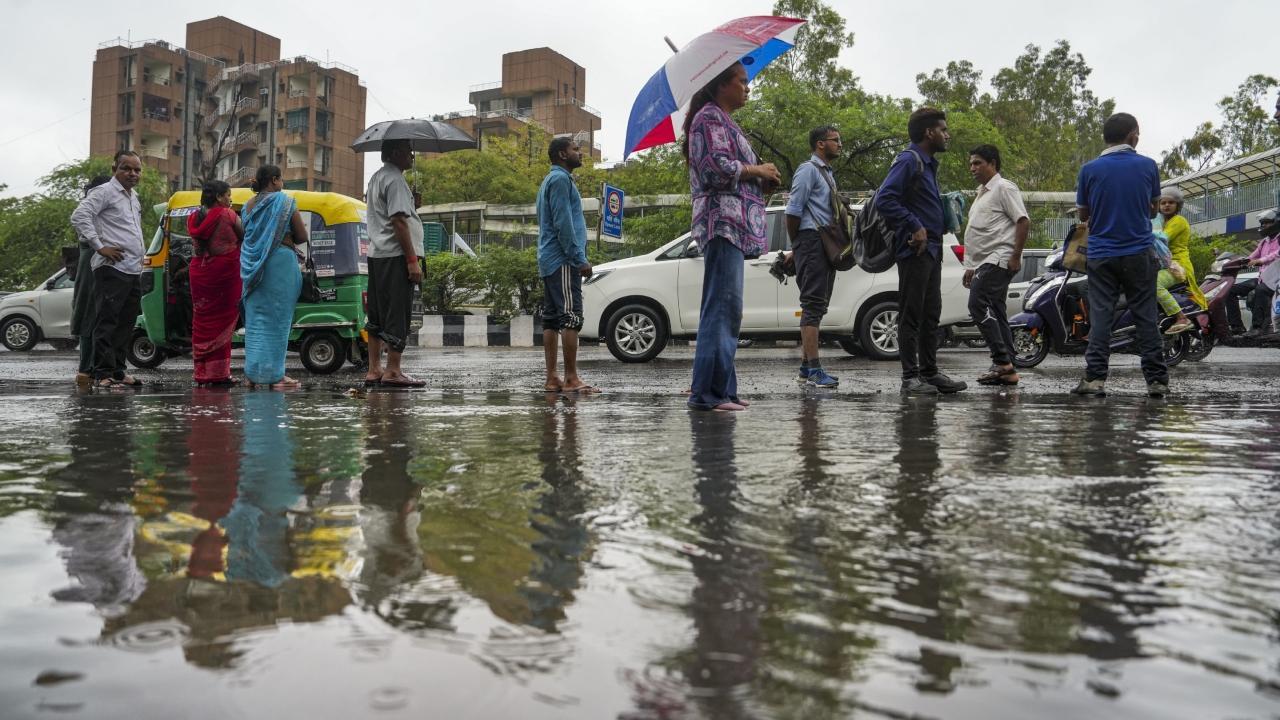 Commuters wait for buses at a stop on a rainy day, at South Extension in New Delhi. Pics/PTI