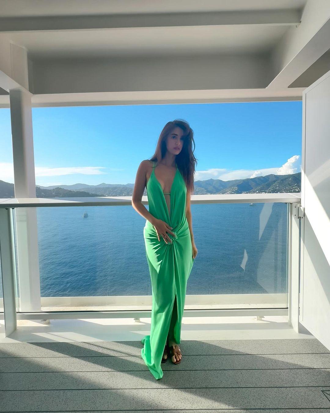 The dress is a beautiful shade of green with a halterneck, a deep plunging neckline, and an open back