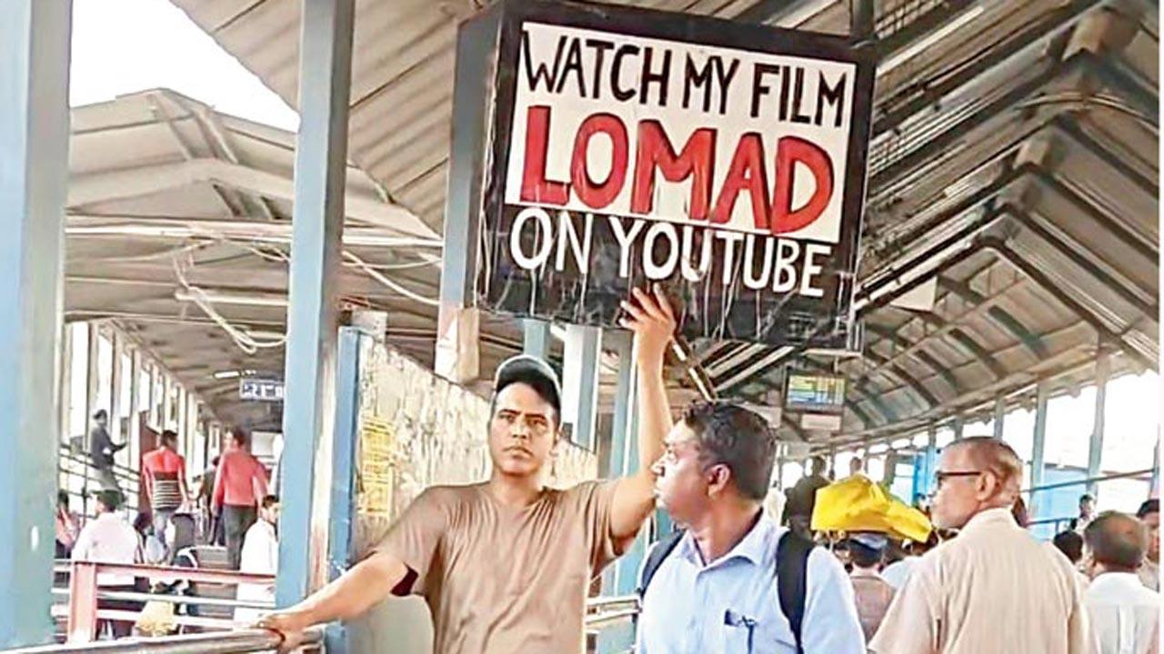 Hemwant Tiwari (left) holds up the placard outside Bandra railway station 