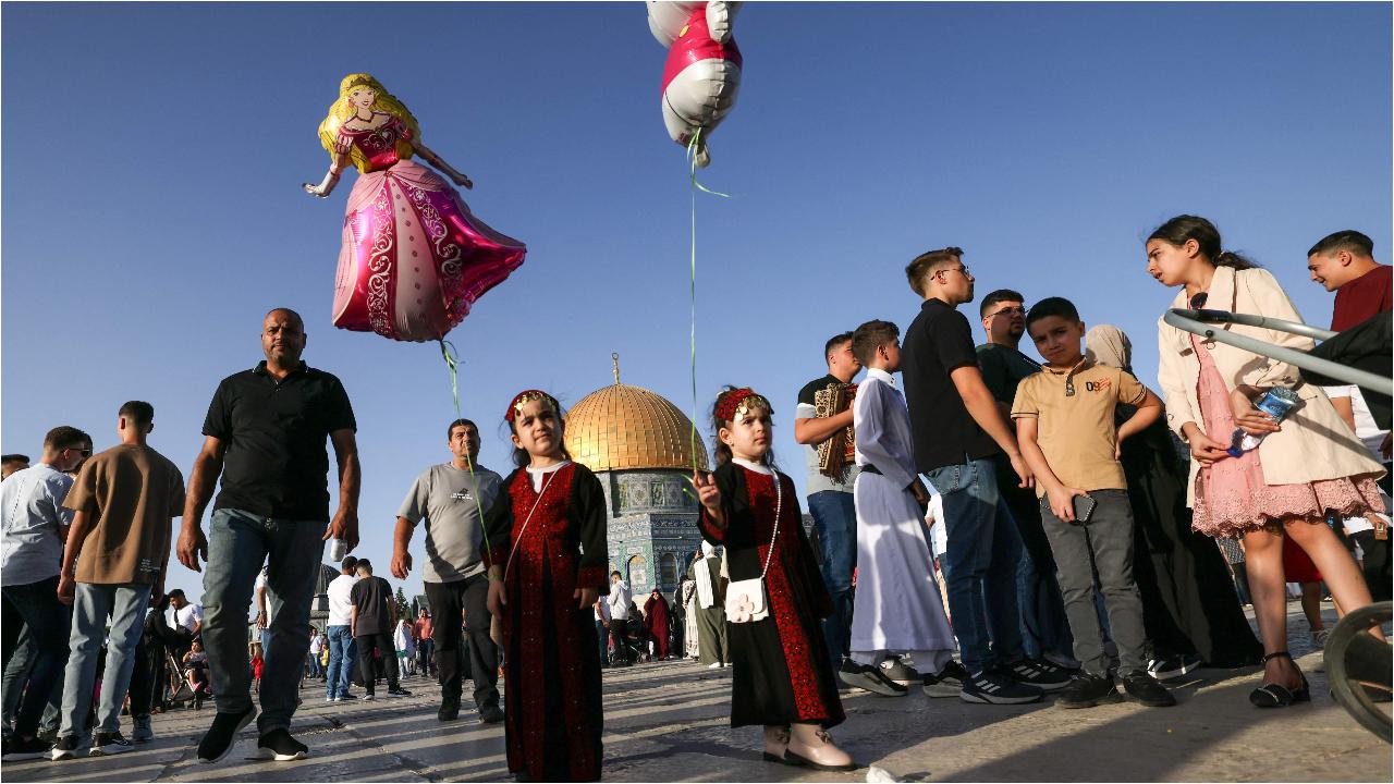 Young girls dressed in traditional outfits fly balloons as Muslims gather at the Al-Aqsa mosques 