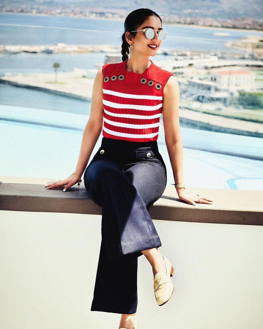 She paired the stylish knit top with wide-leg trousers. Her glamorous makeup featured well-contoured cheeks, a red lipstick, perfectly groomed brows, a glowing highlighter, and subtle eyeshadow.