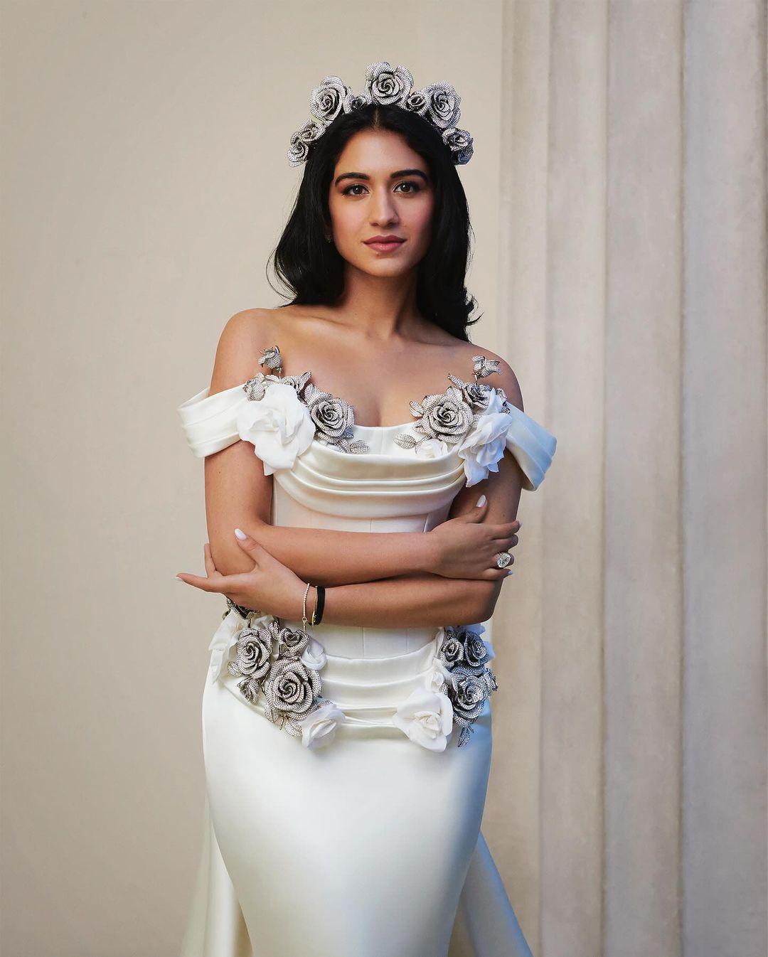 Radhika Merchant wore a beautiful gown with a white silk overskirt decorated with crystal roses. The dress had an off-shoulder neckline, a crystal rose headband, and a long train.