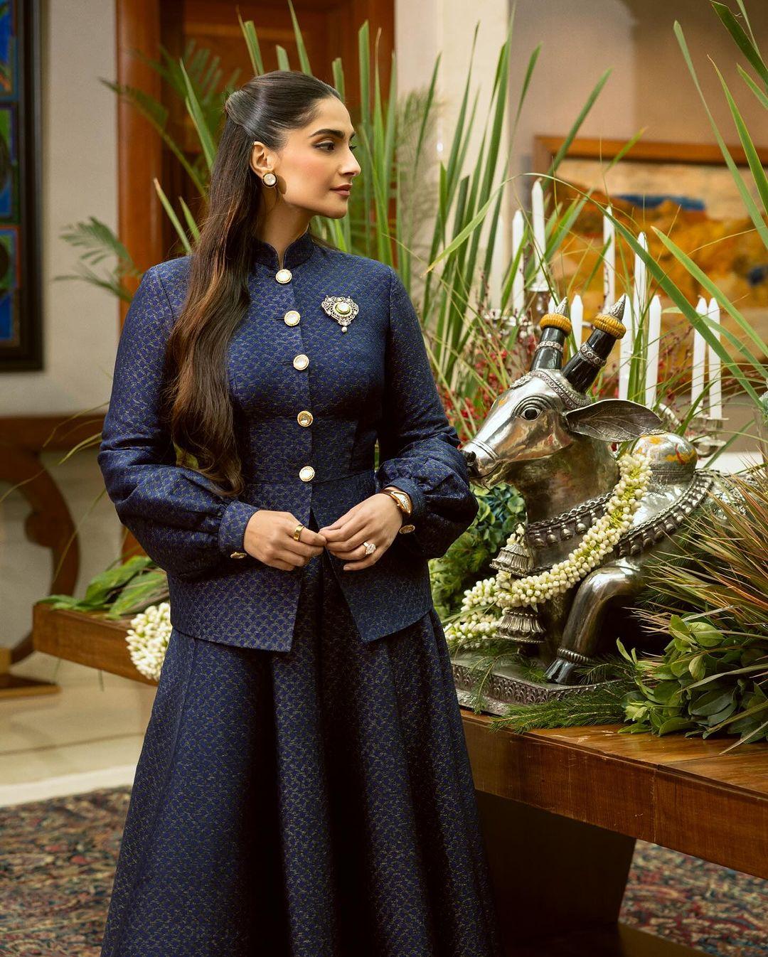 Sonam Kapoor wore a custom royal blue outfit by Kunal Rawal, featuring balloon-like sleeves and a full-sleeved, closed dark blue shirt with golden buttons. The standout piece was a gorgeous golden statement brooch.