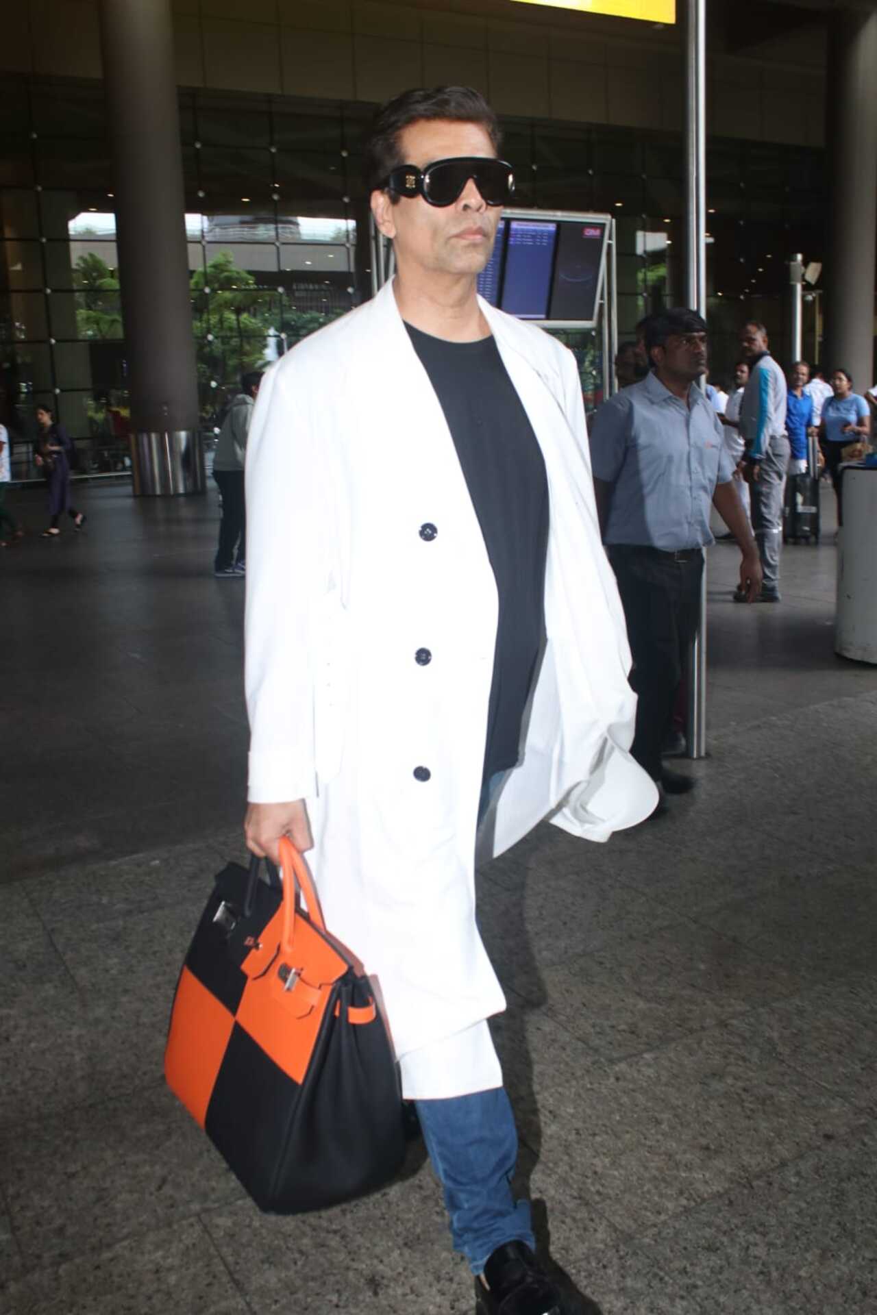 Karan Johar made up for the glamour quotient at the Mumbai airport with his white trenchcoat and a fashionable handbag. 