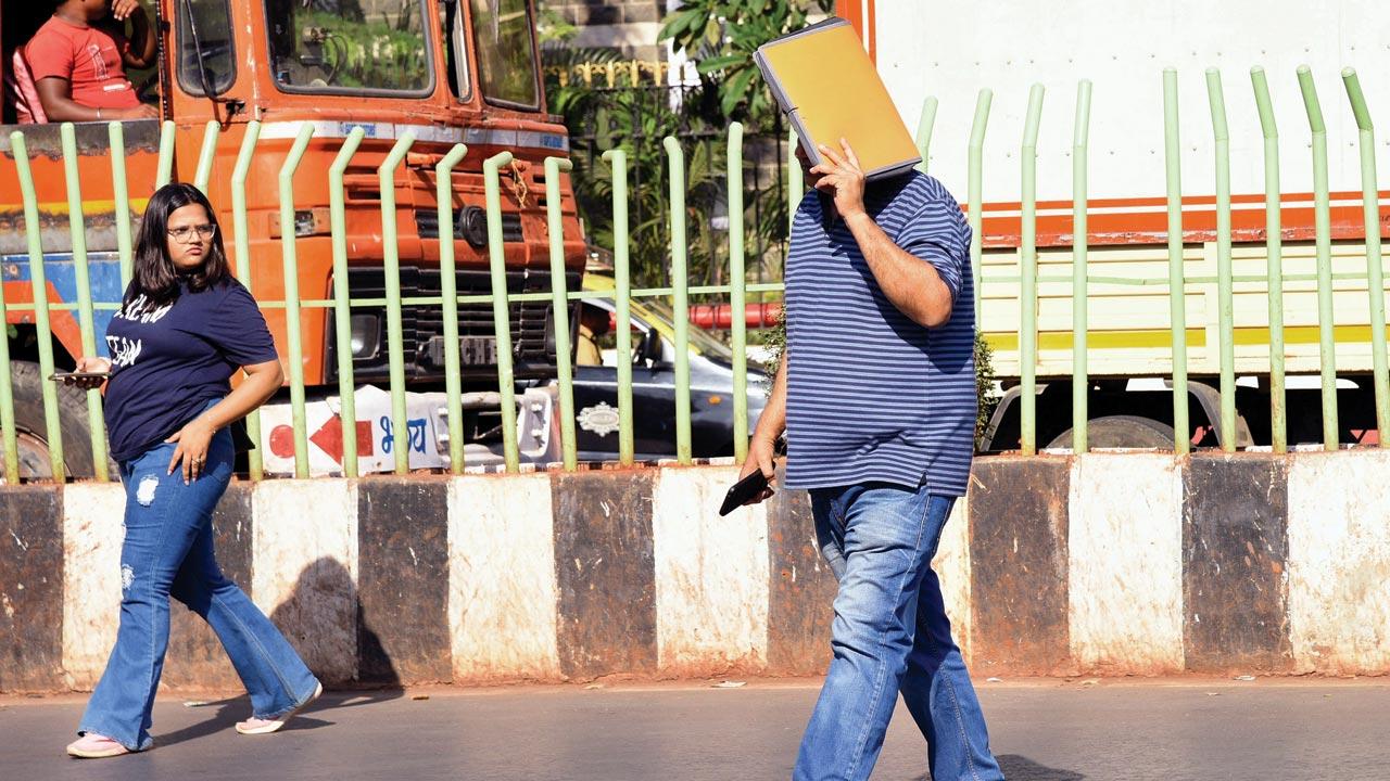 A man shields his face with a file against the scorching sun at Churchgate. Pics/Satej Shinde
