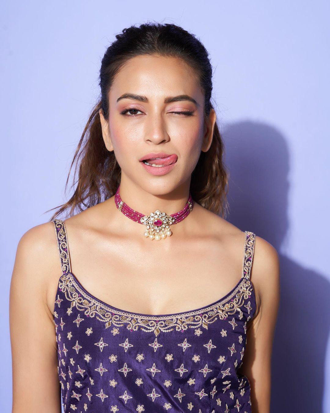 She finished her look with a matching dupatta, tied her hair in a puffed ponytail, and adorned a contrasting pink choker. This look is a perfect fit to ace your appearance in a minimalistic way