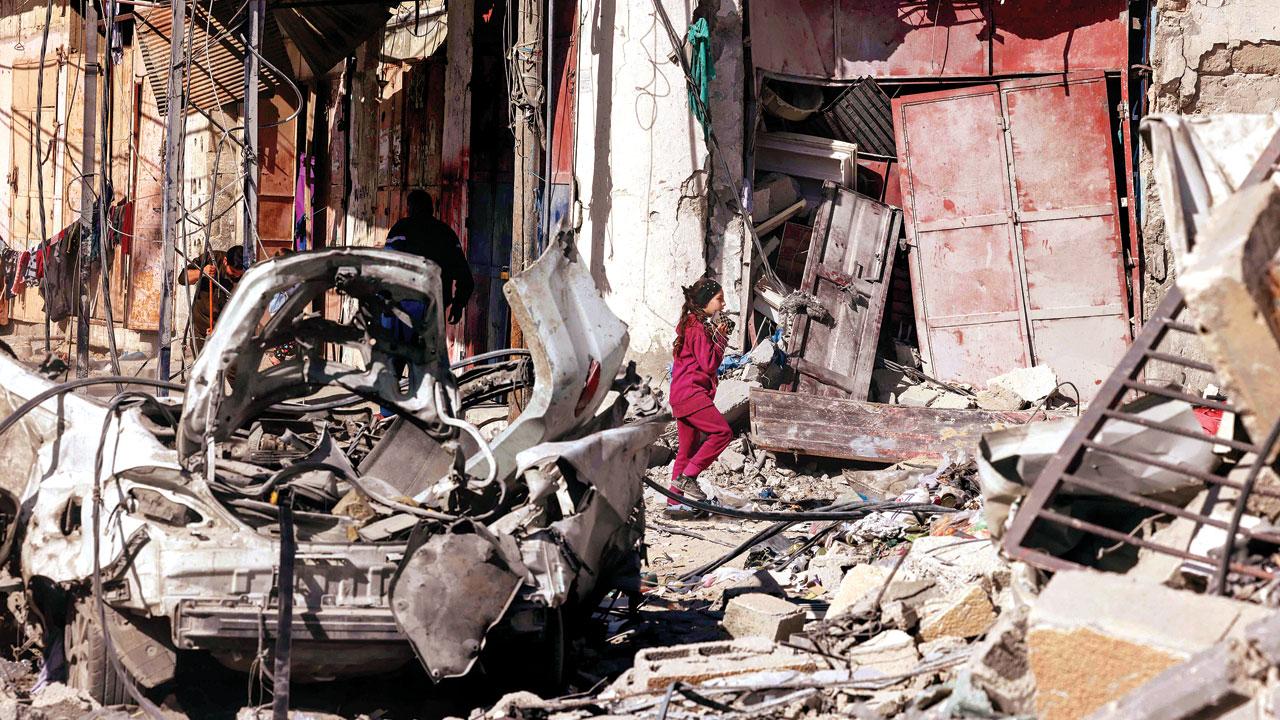 A girl walks past destruction caused by Israeli strikes in Rafah. Pics/AP
