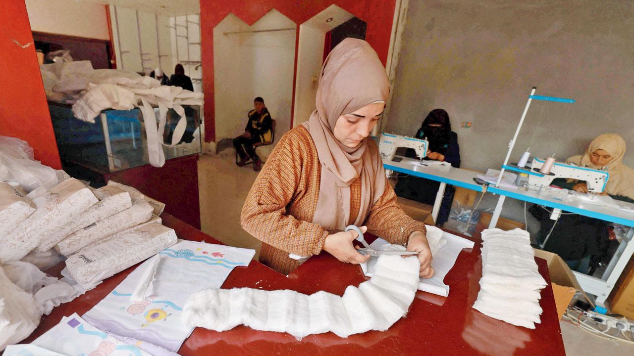 A Palestinian woman cuts material to be used for sewing diapers at a workshop in Rafah. Pics/AP