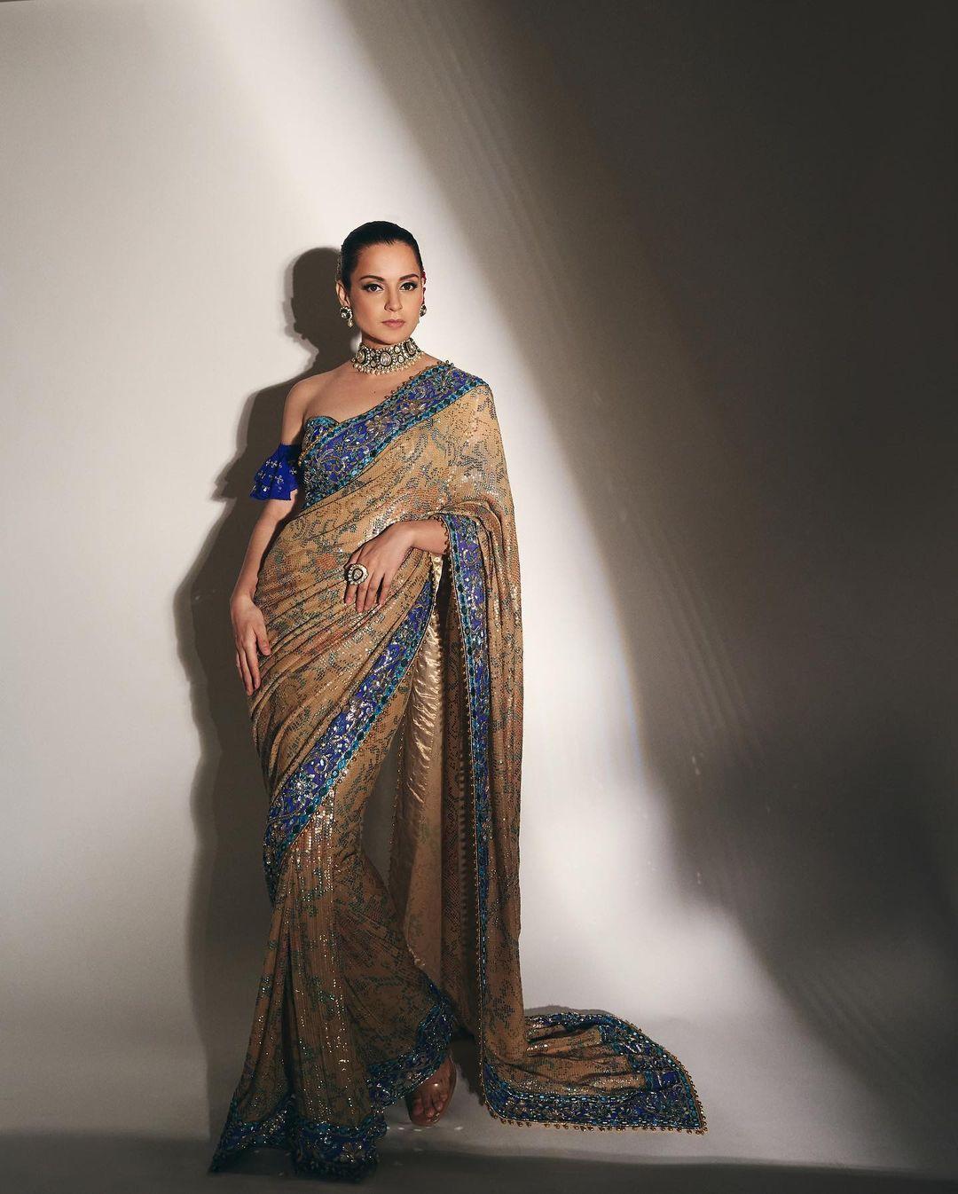 If you are planning to attend any family function, then be ready as we have an amazing outfit choice for you. Kangana wore a beautiful beige saree featuring a contrasting blue border and paired it with an off-shoulder top