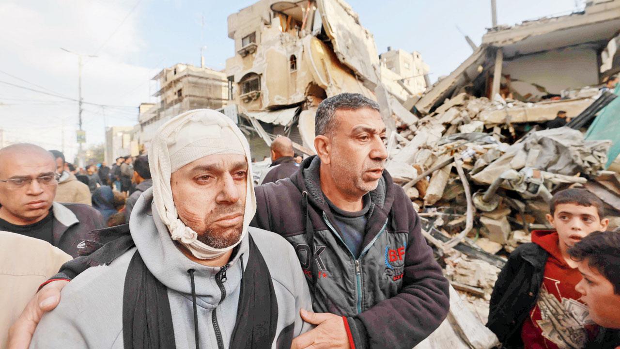 Wounded Palestinian Nidal al-Gharib—who lost his wife and daughter—walks past his neighbours’ destroyed house