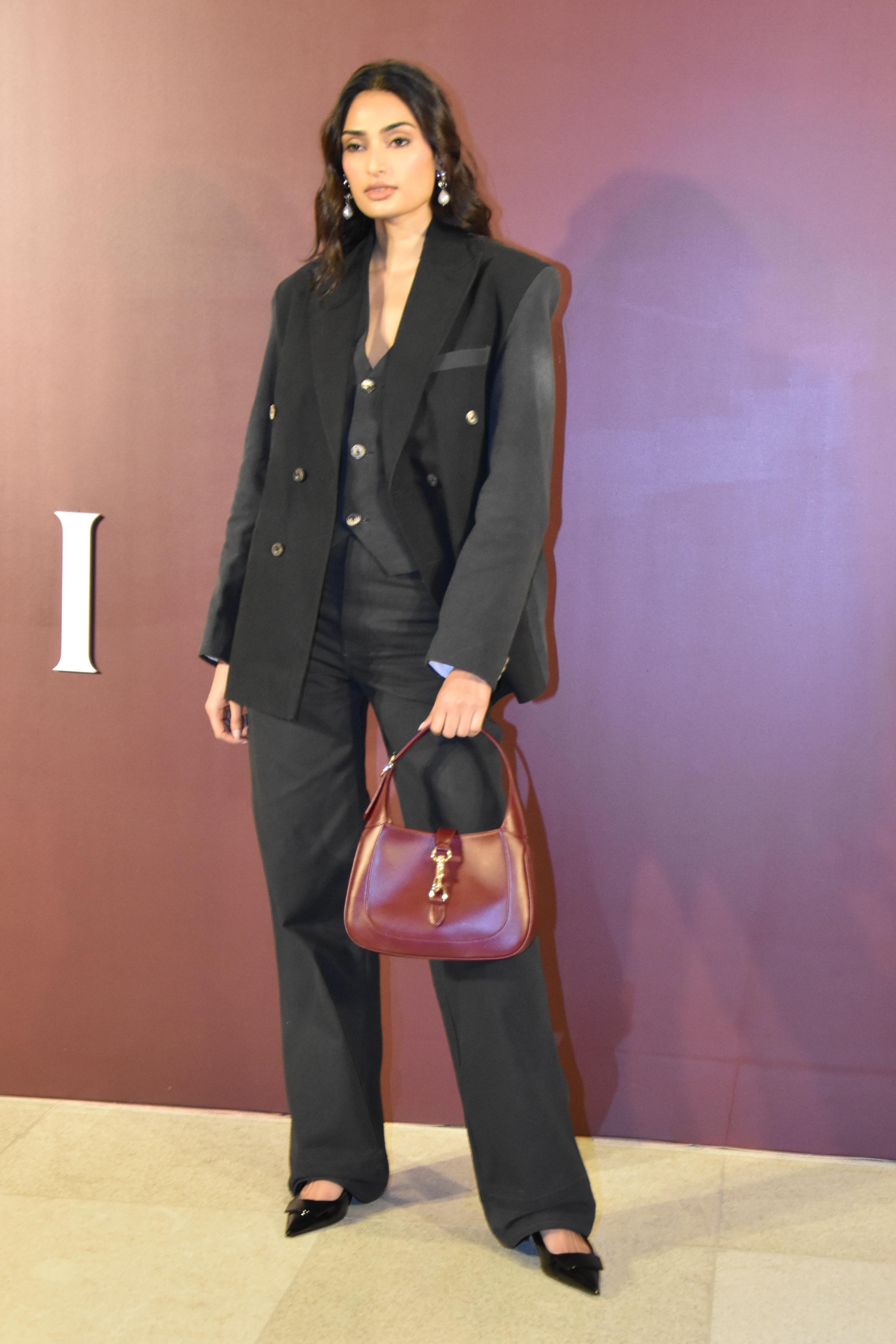 Athiya Shetty captivated in a chic black three-piece ensemble, flawlessly paired with matching sandals. The actress elevated her ensemble with a stunning burgundy purse, creating a perfect contrast that added a touch of sophistication to her look