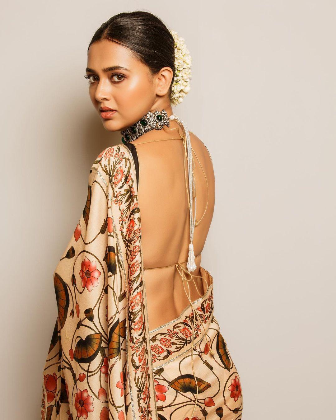 For this look, you need to get a heavily printed white saree, just like Tejasswi's saree. The actress's saree is printed with red and orange-coloured flowers, which makes it perfect for Pooja. After getting the saree, just like the actress, pair it with a contrasting backless blouse to strike a balance
