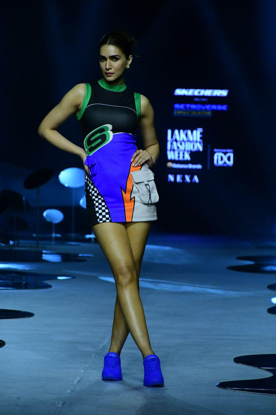 The outfit boasts a round neckline in eye-catching neon green, extending to the sleeves. Vibrant hues of blue and orange inject bursts of colour into the ensemble