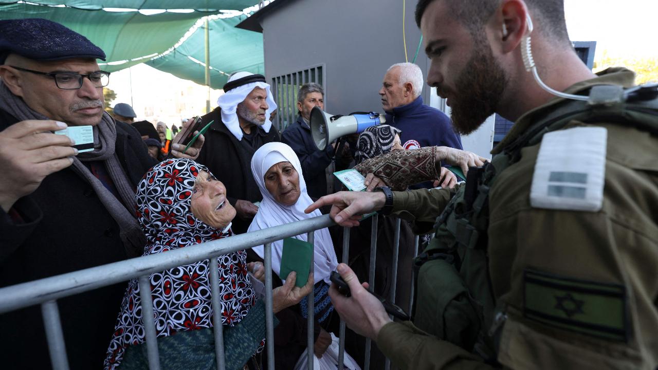 A member of the Israeli security forces checks the identity cards and permits of Palestinians trying to go through a checkpoint in Bethlehem in the occupied West Bank to reach Jerusalem, to take part in the first Ramadan Friday Noon prayer at al-Aqsa mosque compound on March 15, 2024. (Photo by HAZEM BADER/AFP)