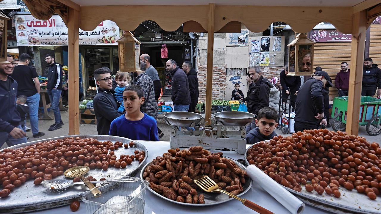 Palestinians walk past a stall of sweets in a market during the Muslim holy fasting month of Ramadan at the Balata refugee camp (Photo by Zain JAAFAR/AFP)