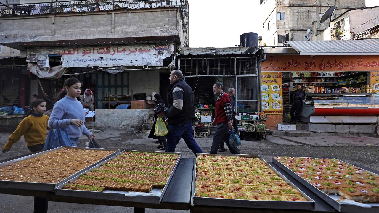 Palestinians walk past a stall of sweets in a market during the Muslim holy fasting month of Ramadan at the Balata refugee camp, east of Nablus in the occupied West Bank (Photo by Zain JAAFAR / AFP)