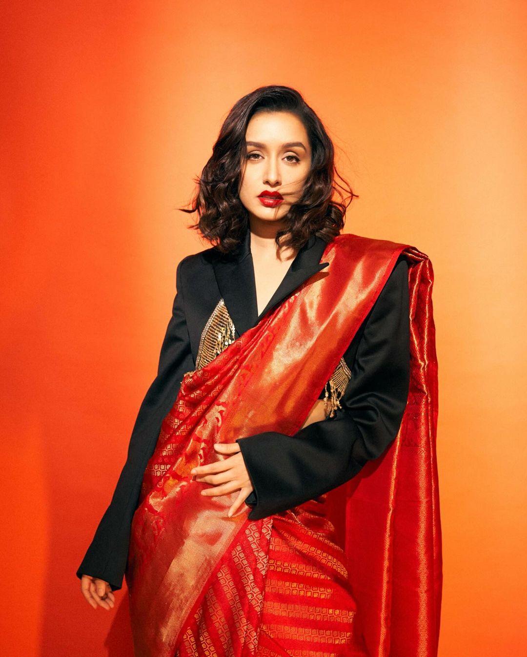 She wore a classic red silk saree, a symbol of timeless elegance. What made the outfit stand out was the unconventional addition of a cropped black blazer adorned with gold accents