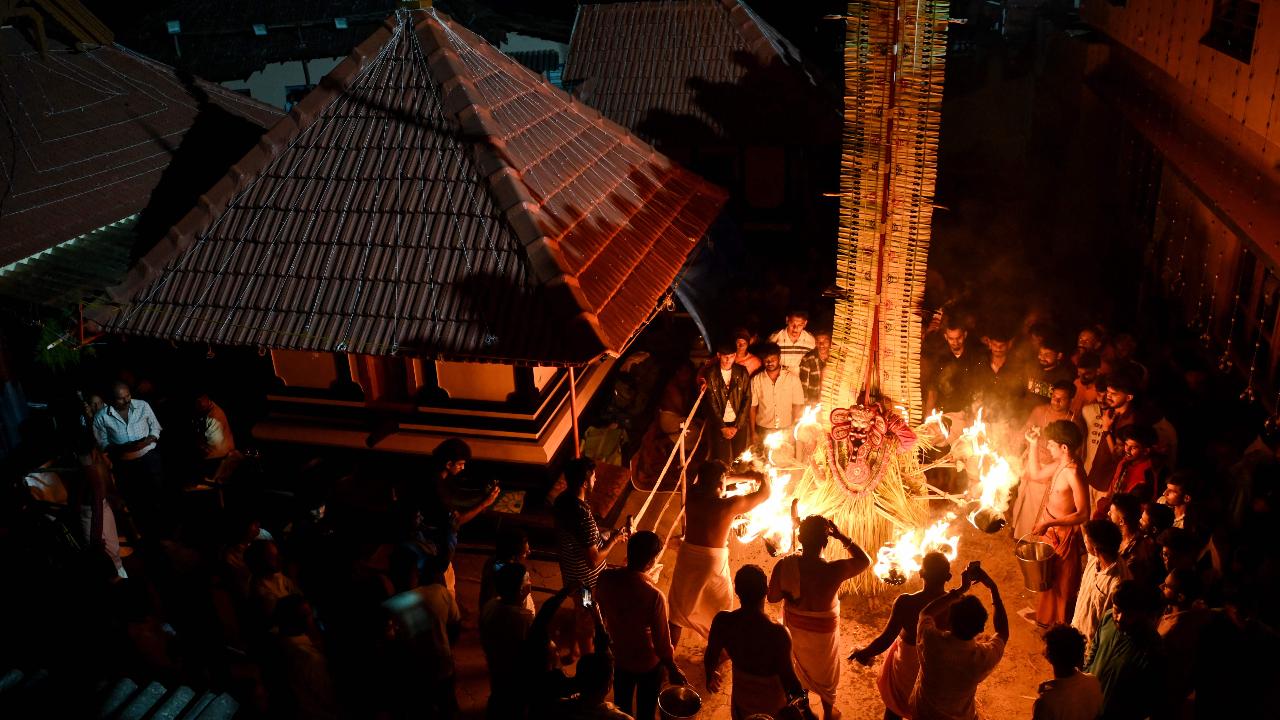 Devotees surround an Indian artist dressed as the Hindu deity Agni Kandakarnan during the traditional dance festival 'Theyyam' also known as 'Kaliyattam', at Muthappa Swami temple in Somwarpet
