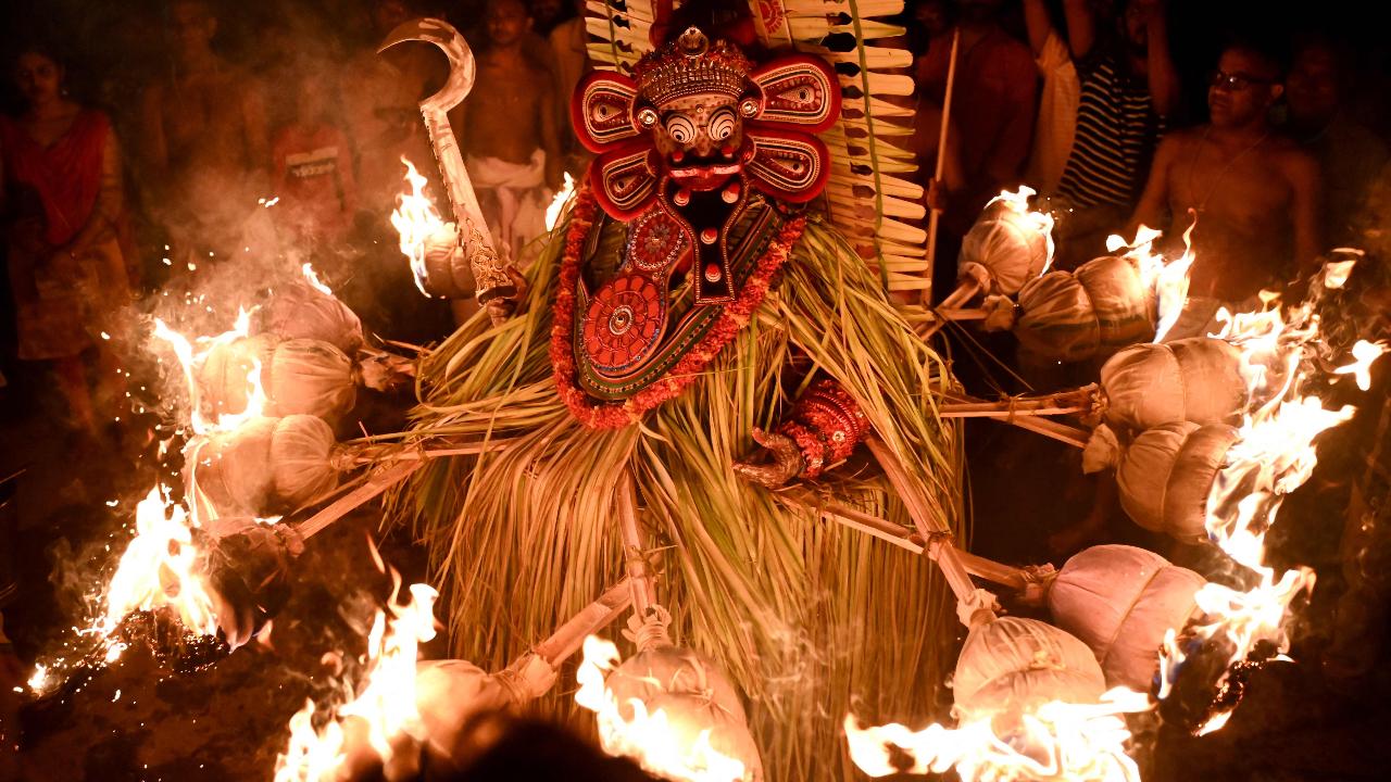 An Indian artist dressed as the Hindu deity Agni Kandakarnan performs with fire wrapped around his costume