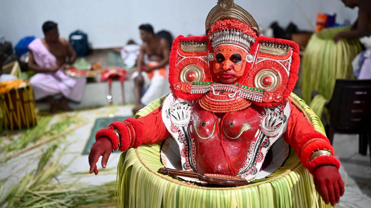 An Indian artist dressed as the Hindu deity Bhagawathy waits to perform during the traditional dance festival 'Theyyam'