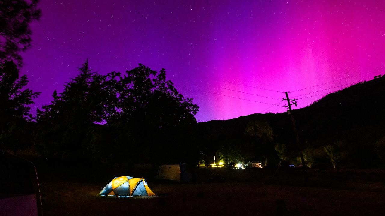 Northern lights or aurora borealis illuminate the night sky over a camper's tent north of San Francisco in Middletown, California on May 11. The storm threatens possible disruptions to satellites and power grids as it persists into the weekend.