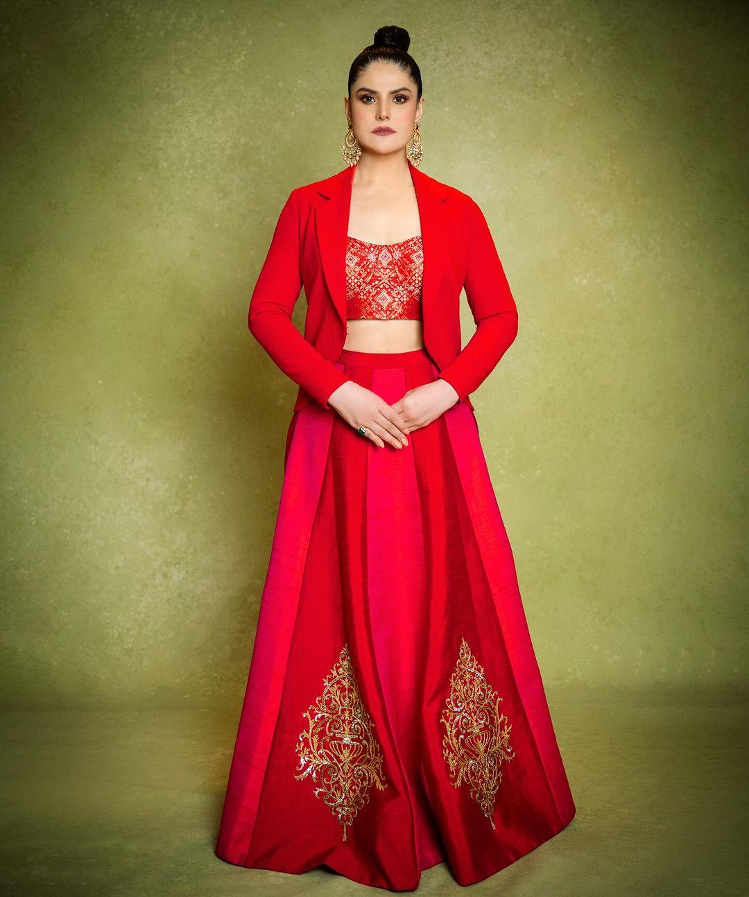 Learn from Zareen Khan how to slay in an indo-western outfit. In this look, she wore a red lehenga with golden embroidery and paired it with a matching printed blouse