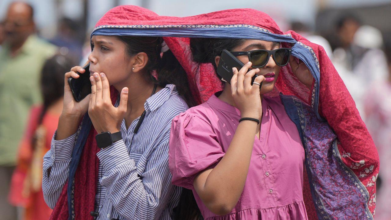 Women cover their heads for protection from the scorching sun on a hot summer day, in Mumbai, Thursday, May 23, 2024. (PTI Photo/Shashank Parade)