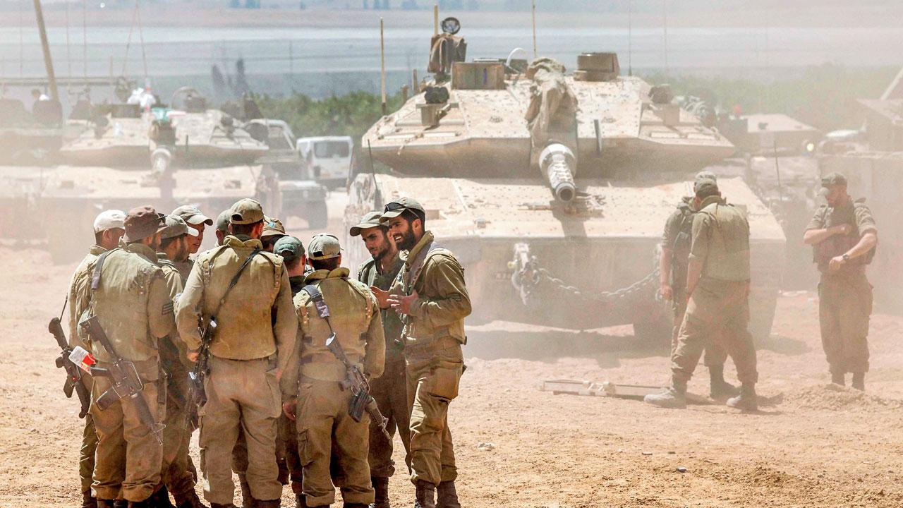 Israeli soldiers huddle before a battle tank positioned in southern Israel near the border with the Gaza Strip on Thursday.