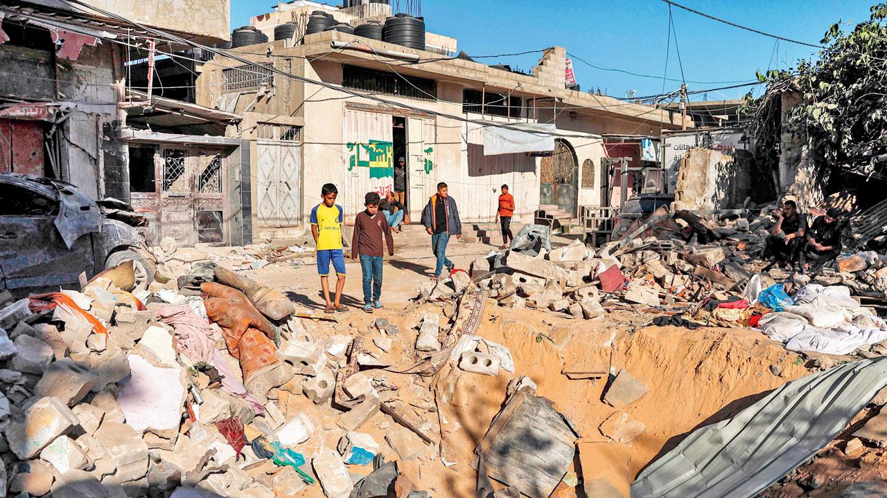 Children stand by a missile impact crater after Israeli bombardment in Rafah. Pic/AFP