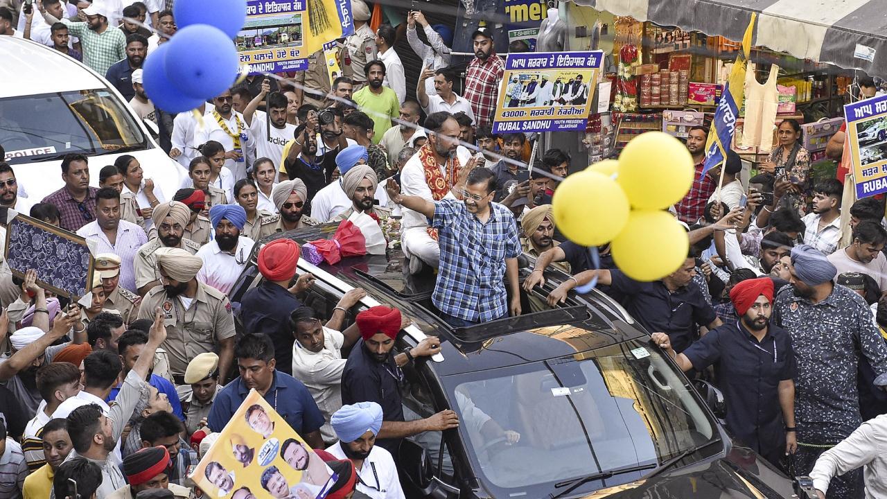 Arvind Kejriwal with party candidate Pawan Kumar Tinu during a roadshow ahead of last phase of general eletions. Pics/PTI