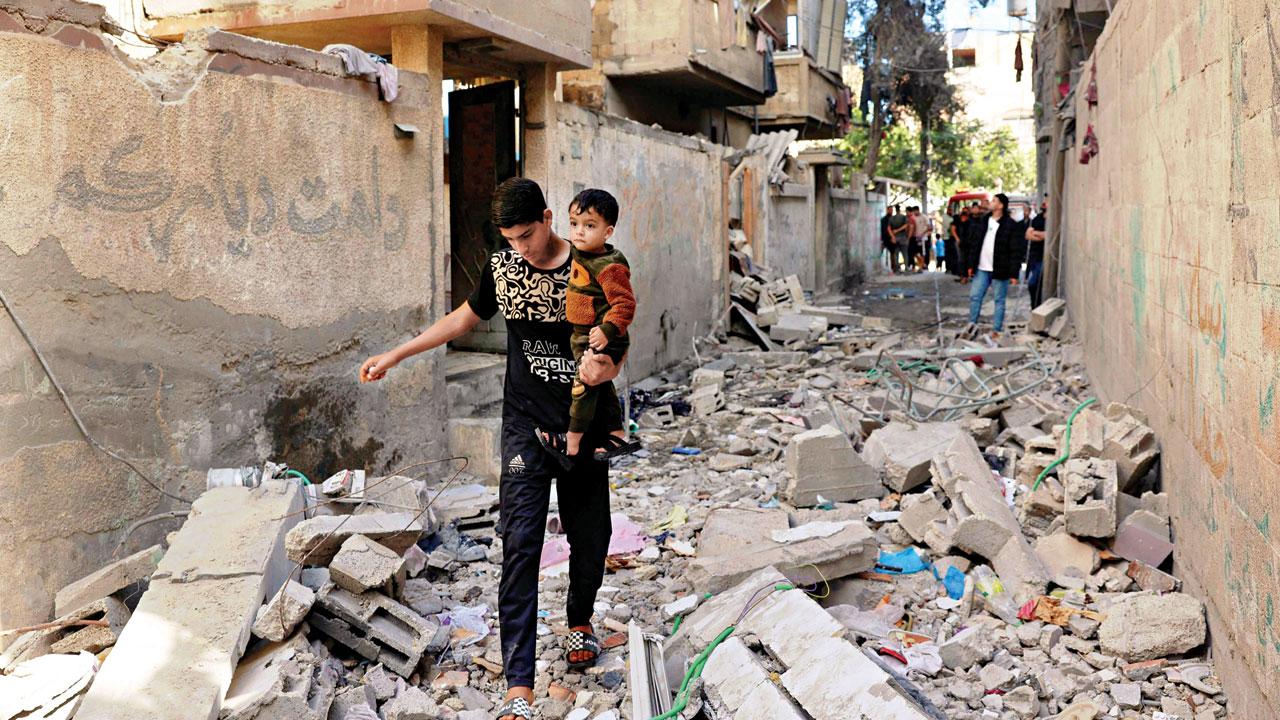 A Palestinian youth with a child walks through the rubble in Rafah’s Tal al-Sultan district. Pic/AFP