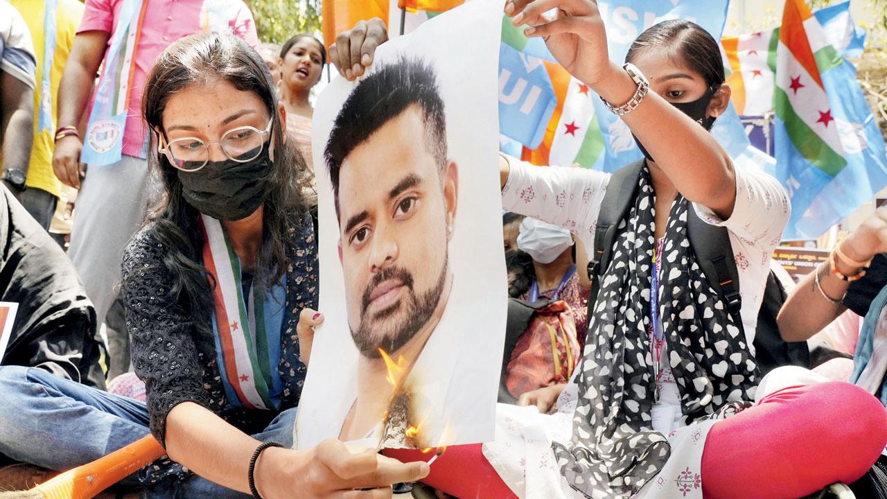 NSUI members burn a poster of Prajwal. pic/PTI