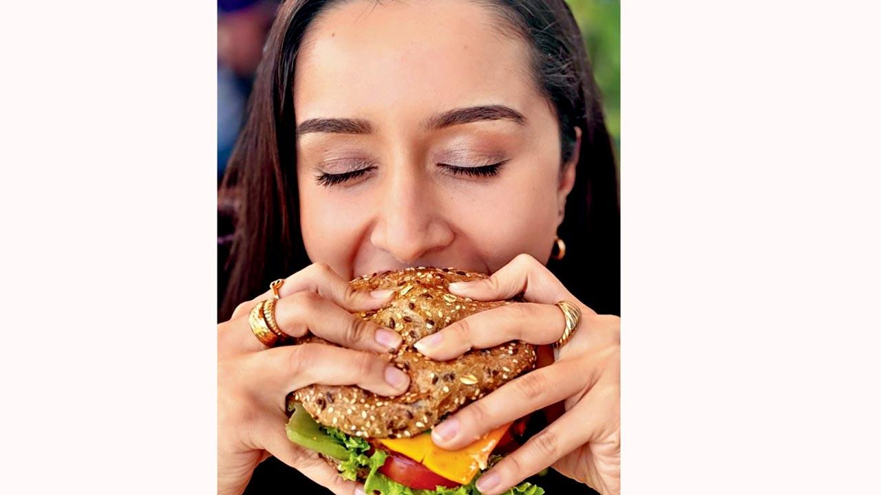 Shraddha Kapoor bites into a burger in a recent post. Pic Courtesy/Instagram