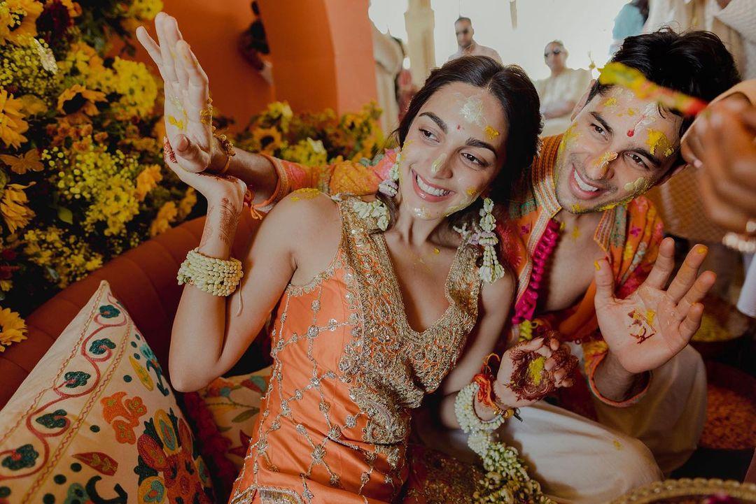 They both dressed in orange outfits, radiating warmth and joy. In one particular photo, Sidharth proudly shows off the intricate mehendi design on his palm, which spells out 