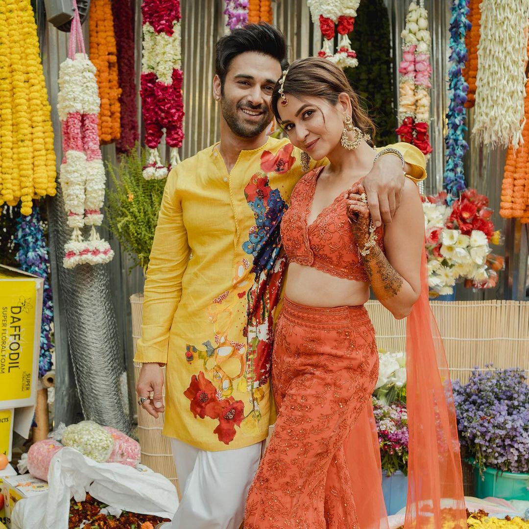 Pulkit wore a yellow printed kurta with white pajamas, while Kriti rocked an orange crop top, palazzo pants, and matching dupatta, accessorized with golden earrings. 