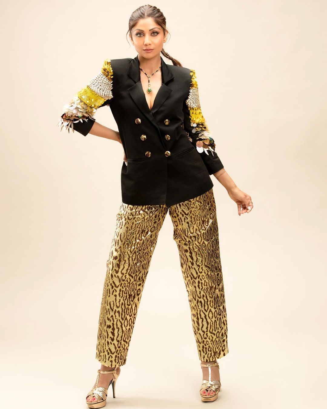 In this outfit, Shilpa Shetty combines eye-catching leopard print pants with a fashionable black double-breasted jacket, featuring striking sleeves. To complete her look, the actress accessorized with a leopard print clutch.