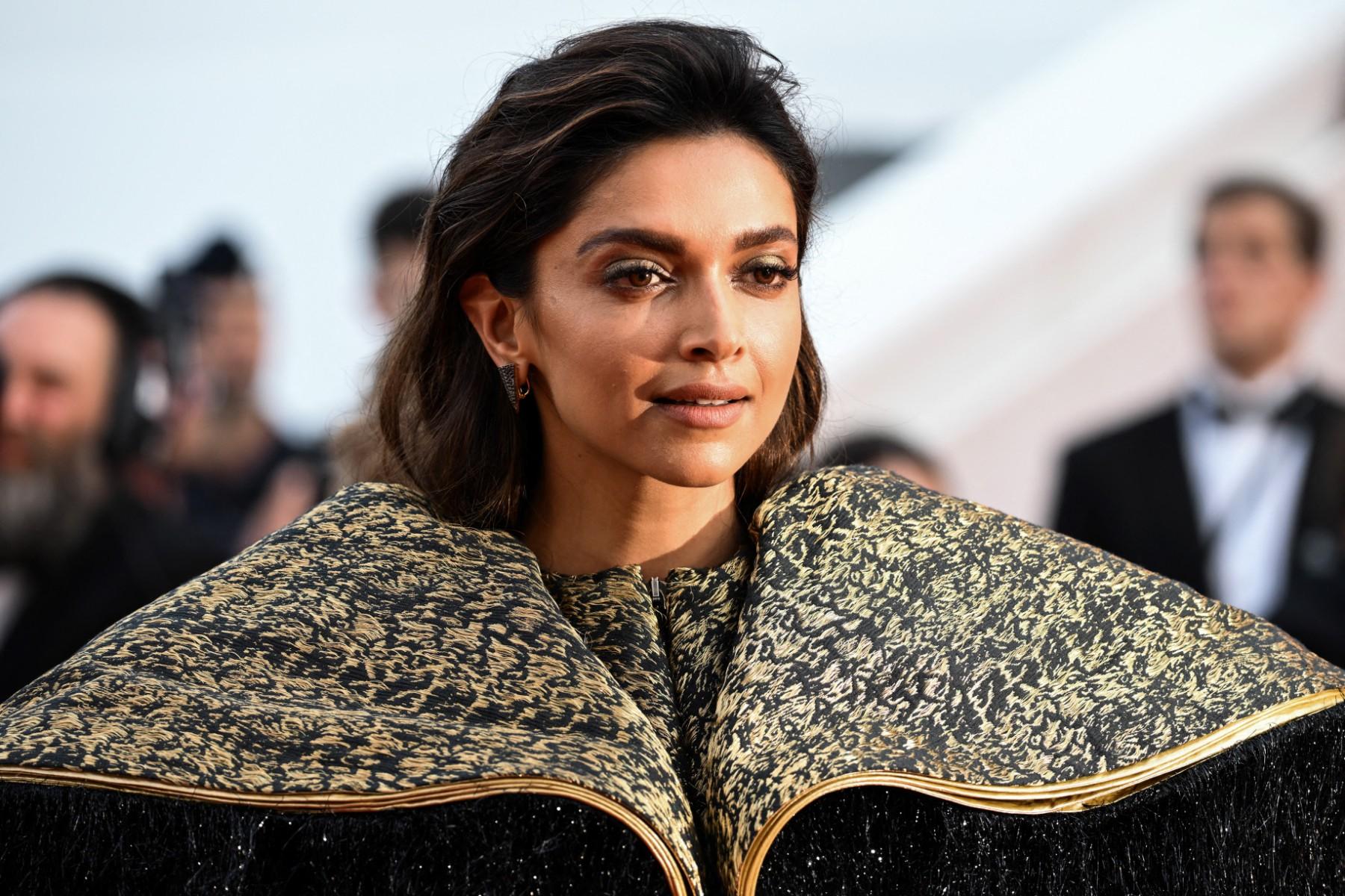 Deepika Padukone donned a striking black and gold gown featuring intricate details that added a luxurious touch. The attention-grabbing element was the dramatic shoulder capes adorned with long, flashy black fringes.