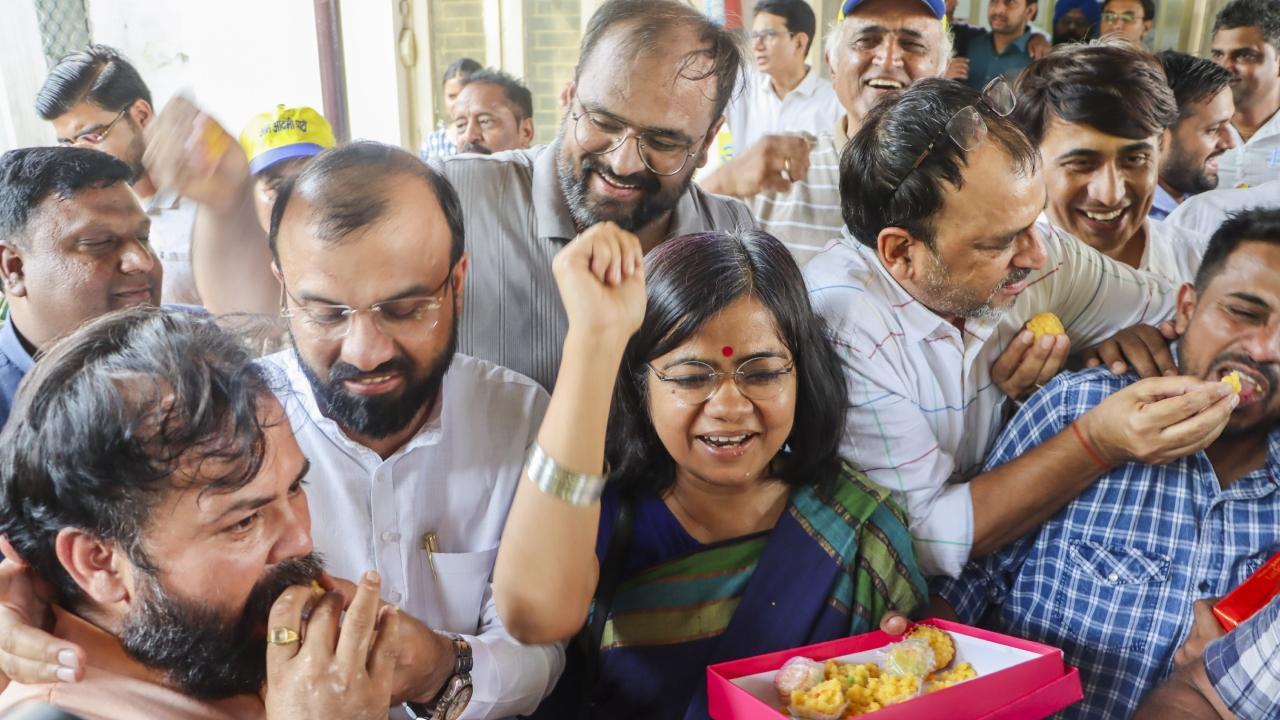 Acitivist of the Aam Adhmi Party (AAP) eat sweets to celebrate at the party headquarters in New Delhi. Pics/PTI and AFP