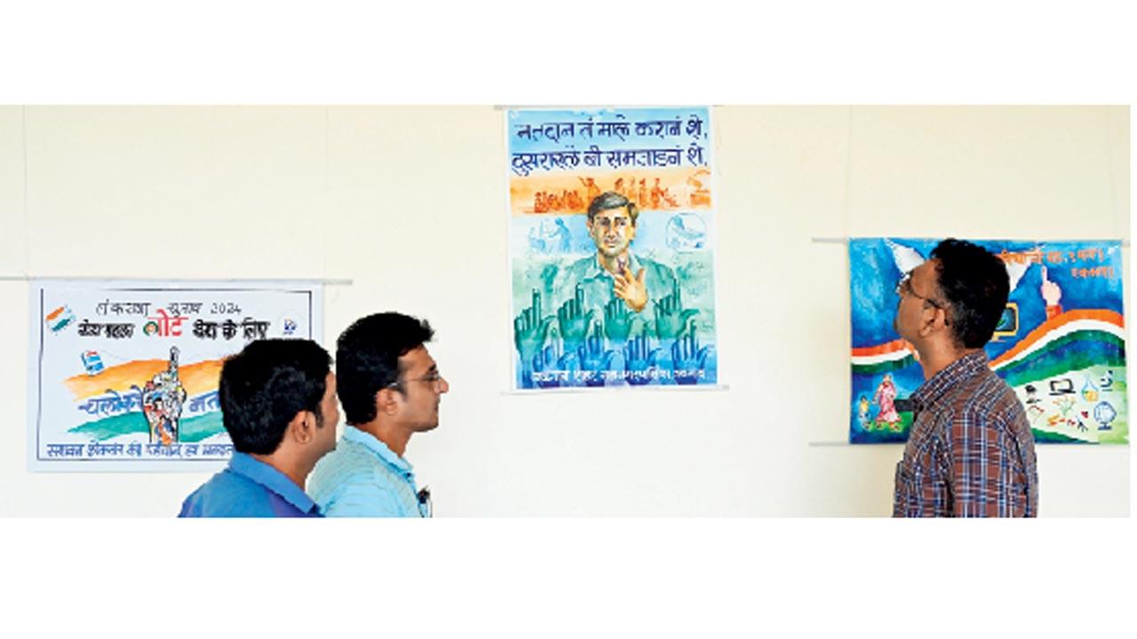 A visitor watches paintings related to the importance of election at an art gallery