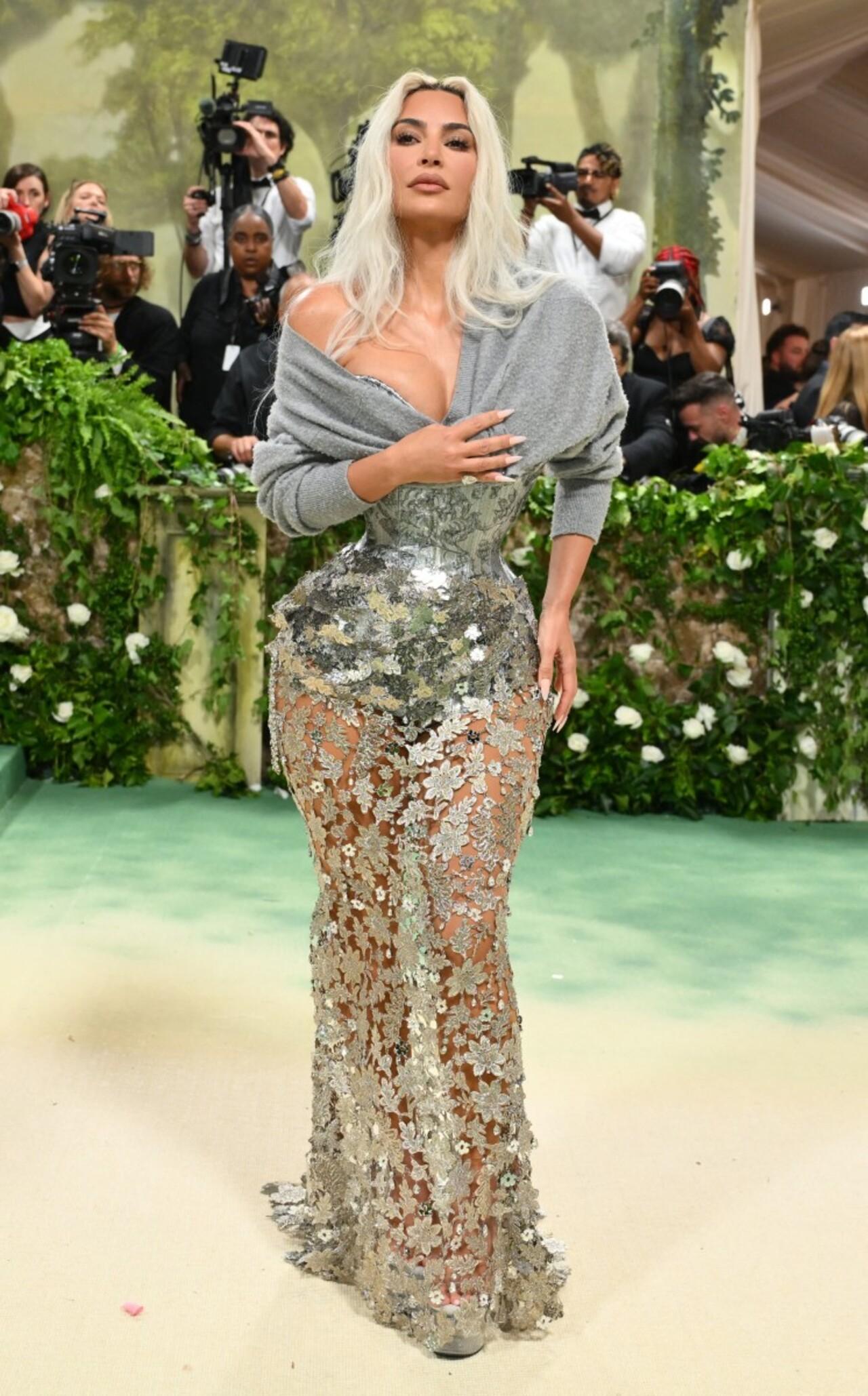 Reality star Kim Kardashian donned a sheer Margiela by John Galliano dress with a lace train featuring leaves and floral accents. The highlight of her outfit was her silver corset, giving her a drastically tiny waist.