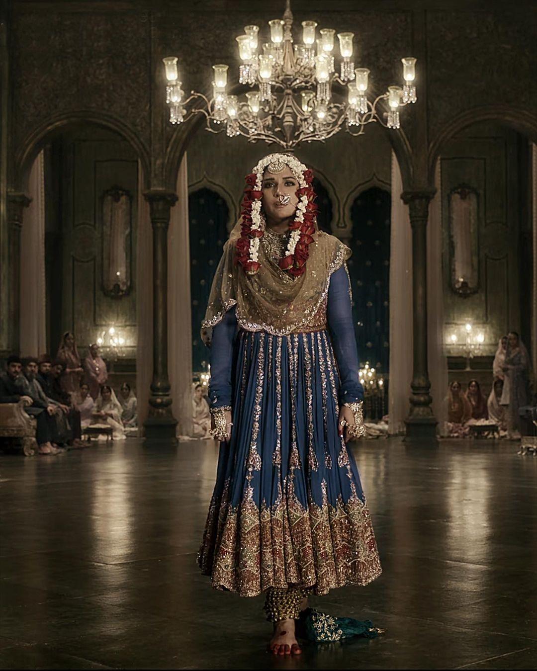 She wears a deep blue dress with a red coat, matching it with a gold scarf for her final dance. The blue colour represents her troubled state and the tragic end of her relationship, blending with the green tones of the ballroom where she performs.