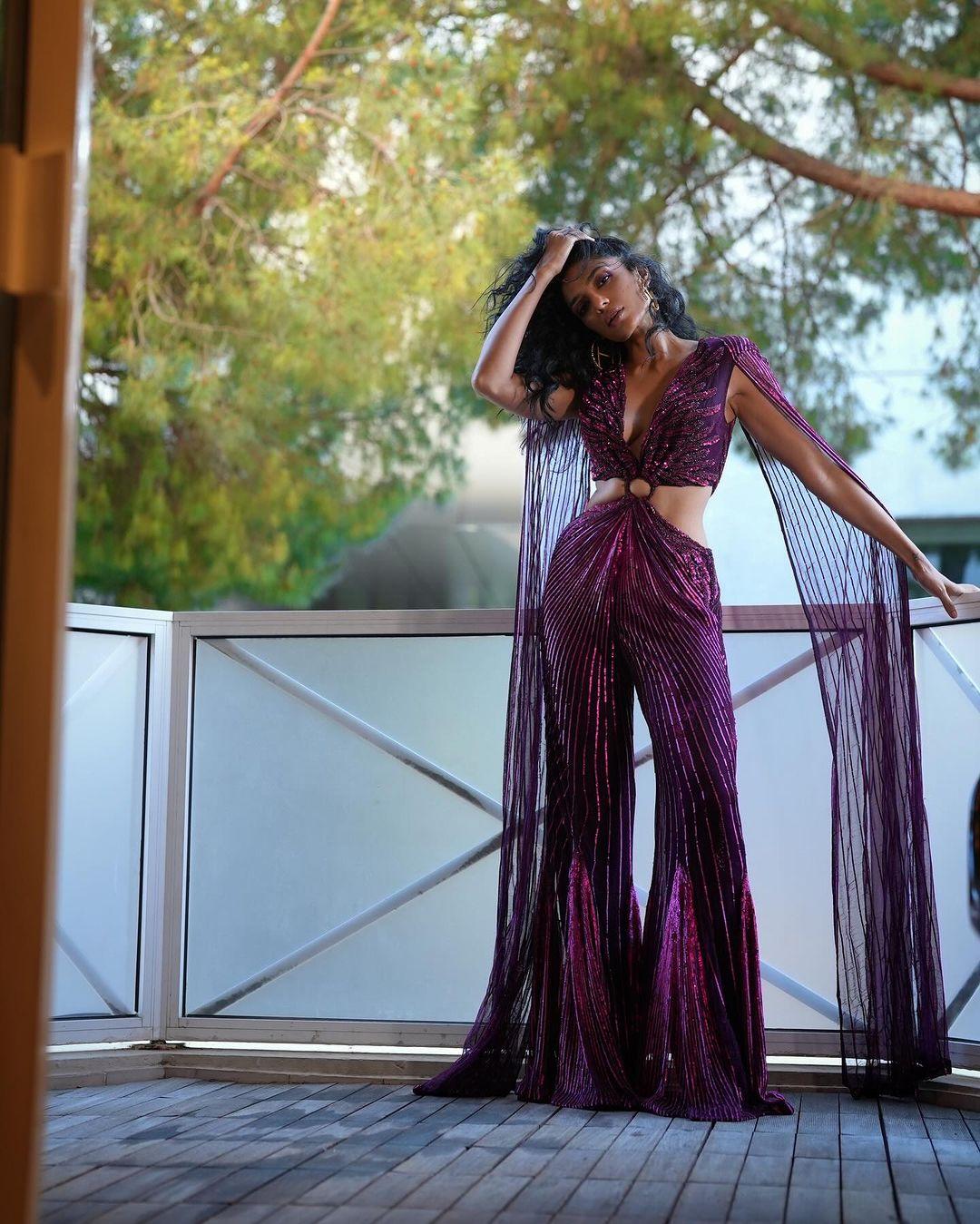 Her jumpsuit was a captivating shade of purple with a deep V-neckline, a striking cut-out at the midriff, and detailed fringe at the bottom.