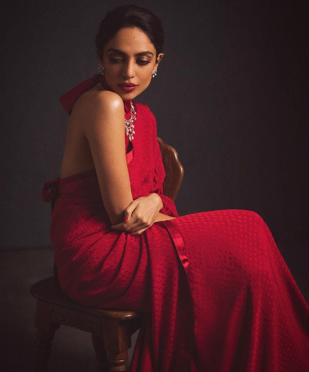 She chose a vibrant red georgette saree for the occasion, paired with a red silk blouse that featured a halter neckline and sleeveless design. 