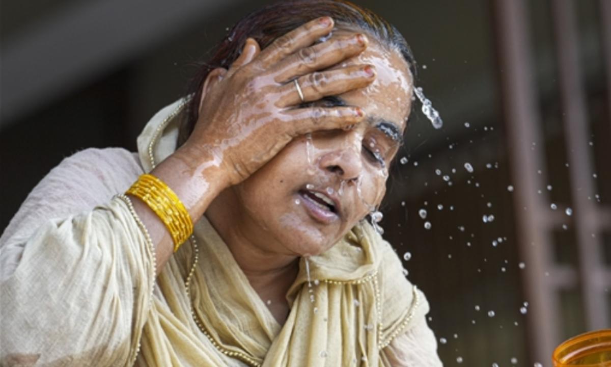 Woman splashing water on face for relief from heat